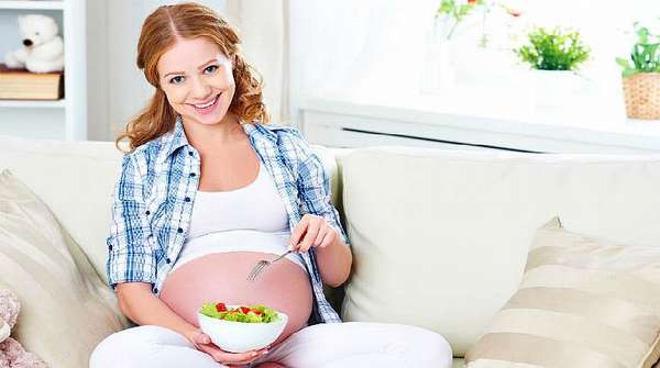Беременная девушка ест салат из овощей