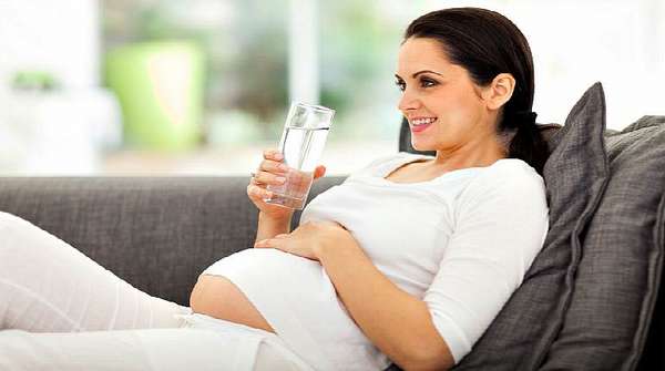 Беременная женщина со стаканом с водой
